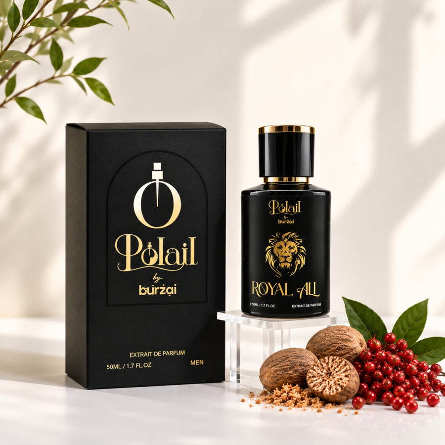 A bottle of Polail by burzai Royal All perfume next to its black packaging box, styled with natural ingredients like whole and cracked nuts, red berries, and green leaves on a white surface with soft leaf shadows.
